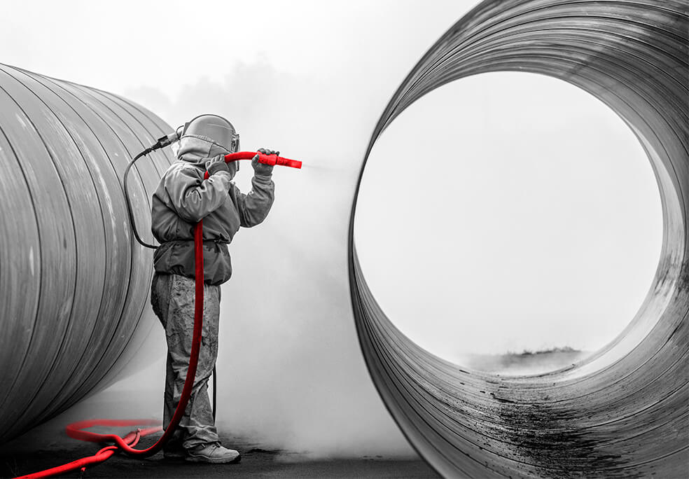 worker cleaning large tube with hose